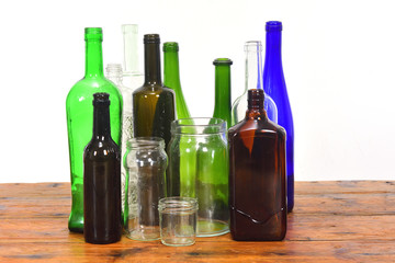 group of bottles and glass jars on a wooden table with white background