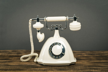  old white telephone on wooden table with color wall background