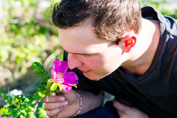 Junger Mann riecht an einer Blume