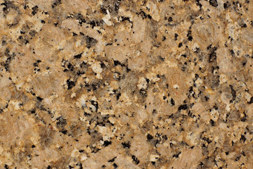 Natural stone yellow-brown granite with dark patches