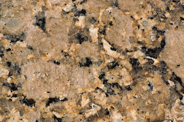 Natural stone yellow-brown granite with dark splashes and cracks