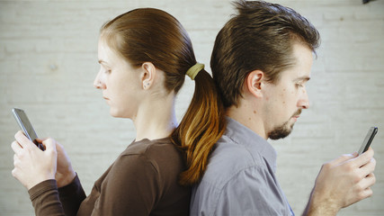 Man and woman back to back on the smartphones