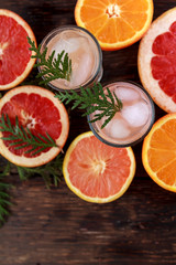 Alcoholic cocktail with grapefruit and citrus, ice and juice, drink glass on a wooden board, old rustic style.