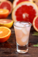 fresh grapefruits sliced and a tall glass filled with juice and vodka with ice