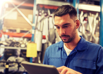 car service, repair, maintenance and people concept - auto mechanic man or smith with tablet pc computer at workshop or warehouse