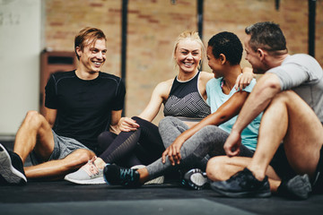 Laughing friends sitting in a gym after working out