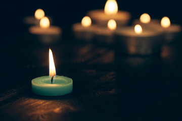 candles burning in darkness over black background. commemoration concept.