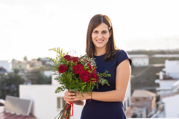 Nice happy young woman with bouquet of red roses