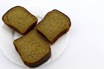 On a white round plate is black bread made from wheat and rye flour, without filling. White background