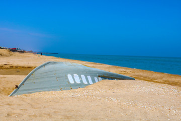 Old inverted fishing boat on the sandy shore. Seascape 