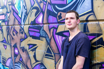 Junger mann steht in der Stadt vor Graffitis.