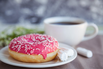 Glazed donut with black coffee and marshmallows. Pink tasty donut on a table. Morning breakfast.