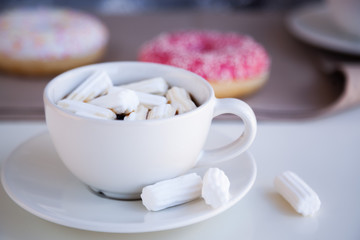 Fototapeta na wymiar Black coffee with glazed donuts and marshmallow. Pink tasty donut on a table. Morning breakfast.