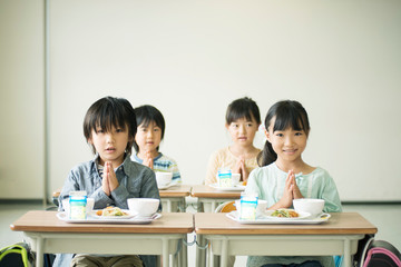 給食を前に手を合わせる小学生