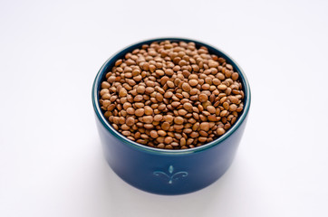 Blue bowl of dried lentils on white background