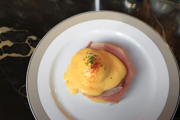 Egg Benedict with ham on white dish, English breakfast.