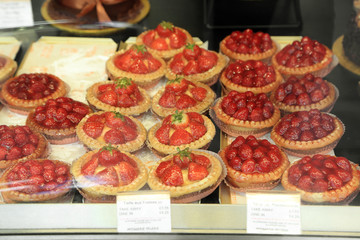 Tasty appetizing confectionery, strawberry tart pie and rasberry tart pie on a counter show window.