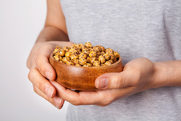 Woman's in hand roasted and dry chickpeas in a bowls.