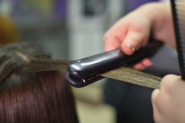 hair dresser making hairstyle with iron