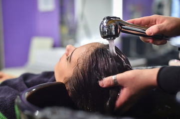 young woman in hairdresser salon washing hair