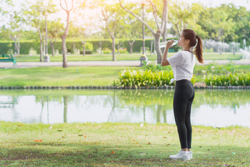 Sporty woman drinking water after her training in the park at the morning.healthy lifestyle concept...