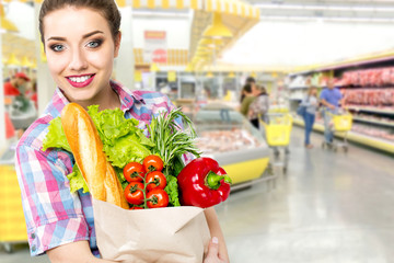 Smiling happy woman enjoying shopping at the supermarket, holding vegetables in eco friendly bag