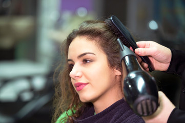 young woman in hairdresser salon drying hair