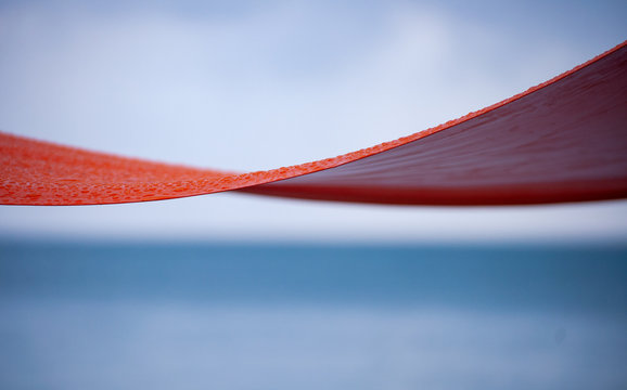 Paisaje abstracto de curvas con una lona naranja y fondo de nubes y mar