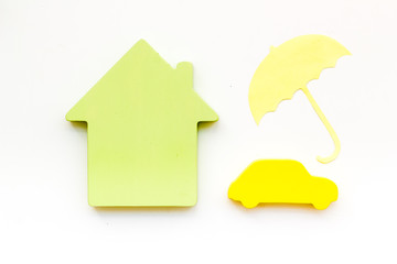 Car buying and insurance concept with car, house and umbrella figures on white background top view