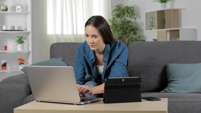 Serious Woman Talking On Phone Using Multiple Devices At Home