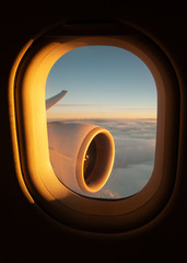View out of an airplane window of the jet's wing and engine whilst the sun sets