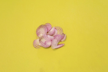 Sliced shallot (red onion) on green plastic chopping board.