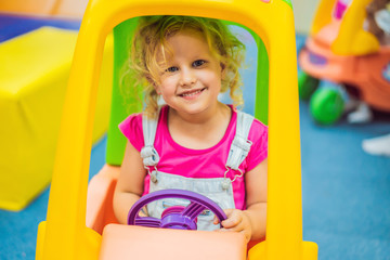 Fototapeta na wymiar Little girl rides a toy colorful car