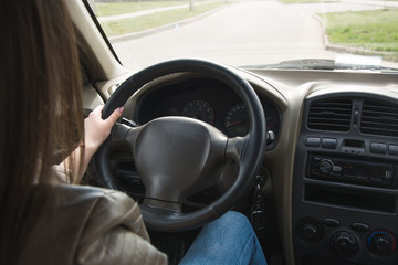 The girl goes behind the wheel of a car, hands on the steering wheel. Driving a large car...