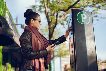 beautiful young woman pays for Parking in meter on the street