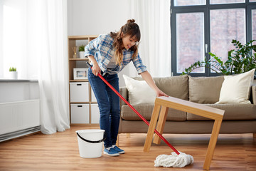 people, housework and housekeeping concept - happy asian woman with mop and bucket cleaning floor...