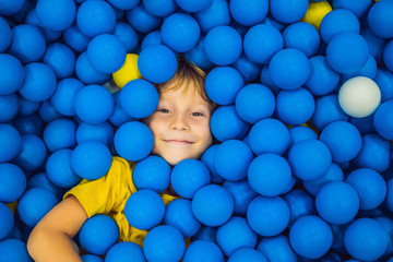 Fototapeta na wymiar Child playing in ball pit. Colorful toys for kids. Kindergarten or preschool play room. Toddler kid at day care indoor playground. Balls pool for children. Birthday party for active preschooler