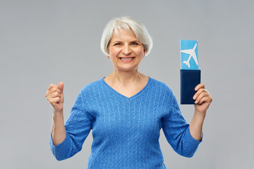 tourism, travel and vacation concept - happy senior woman with passport and airplane ticket over grey background