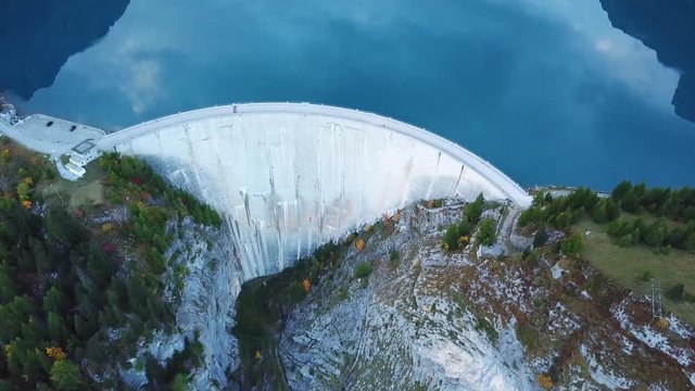 Water dam and reservoir lake aerial drone footage in Swiss Alps mountains generating hydro electricity power renewable energy and sustainable development. 4K 60fps video