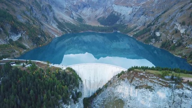 Water dam and reservoir lake aerial drone footage in Swiss Alps mountains generating hydro electricity power renewable energy and sustainable development. 4K 60fps video