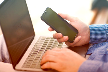 Businessman working with modern devices. Close up male hands, smart phone and laptop. Business, technology, office concept. 