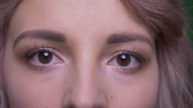 Close-up shot of beautiful model opens eyes watching calmly and modestly into camera.