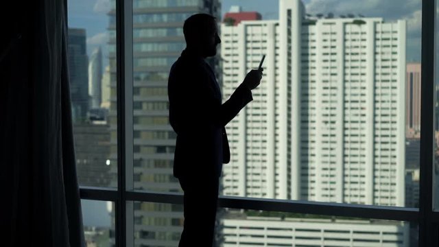 Businessman texting on smartphone by window in office