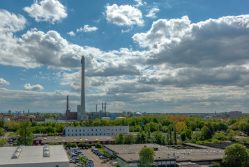 Fototapeta premium Aerial view of the caravans of the carnies standing behind the rides of a fairground. A combined heat and power plant with a long chimney in the back