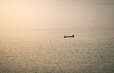 A small boat floating in a lake with town in the morning fog.