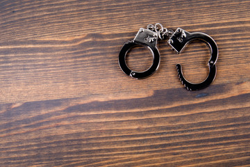 Handcuffs on a dark wood background. Corruption, crime and law