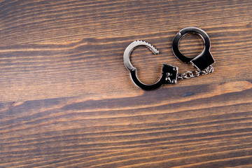 Handcuffs on a dark wood background. Corruption, crime and law