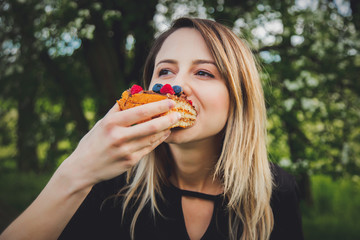 Woman eating a chocolate covered blueberry and raspberry pice of cake on outdoor