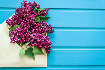 Purple flowers lilac in an envelope over wooden background