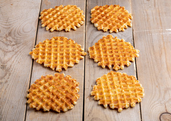 Six fresh baked round waffles laid out on rustic wooden table.